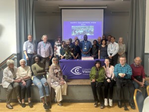 A group of members and volunteers are standing around a table for volunteers week