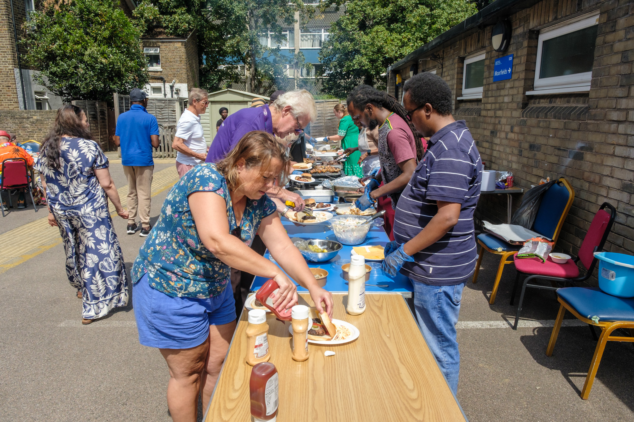 Staff and volunteers serving burgers, salads and other food at the outdoor BBQ.