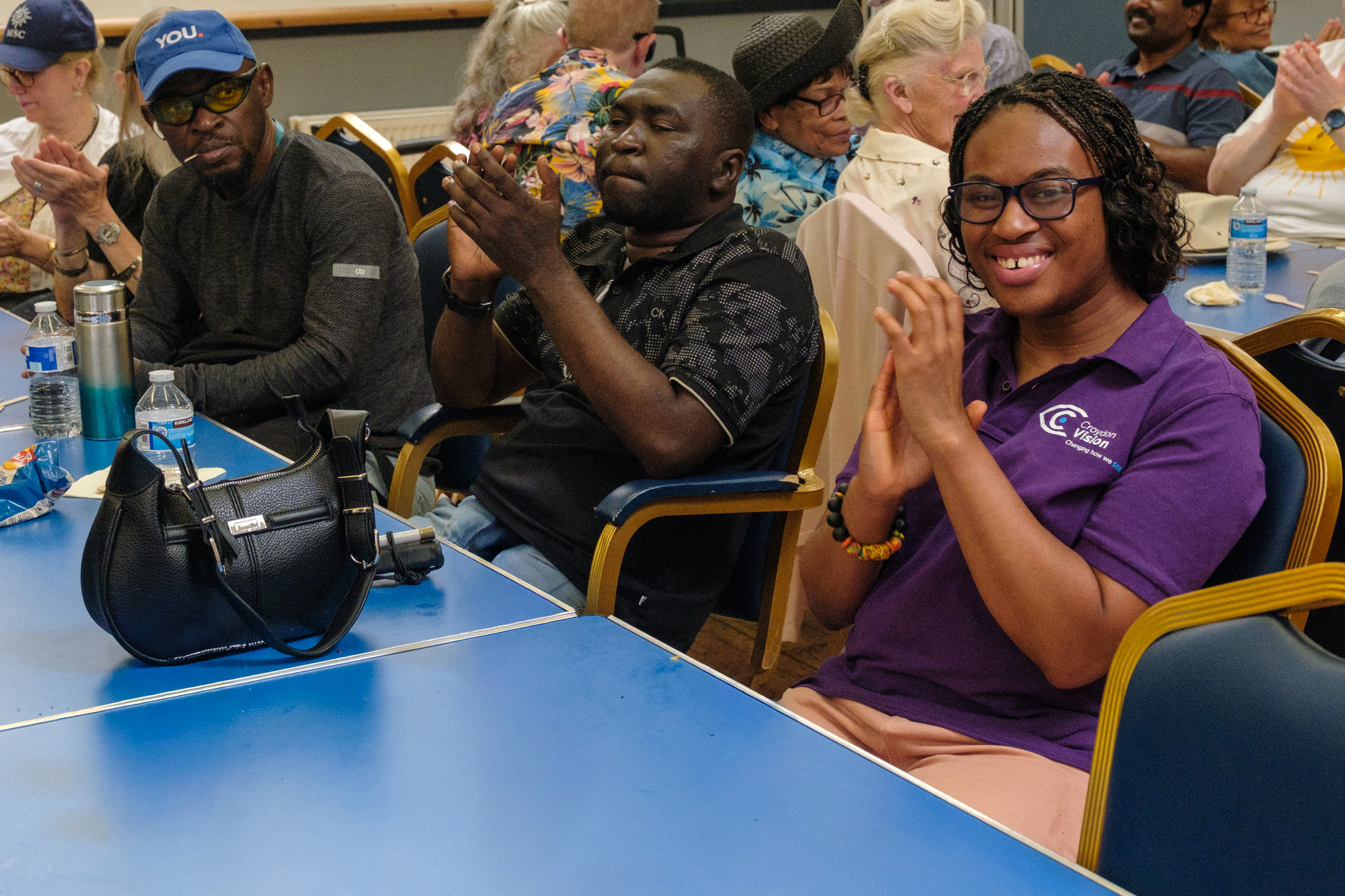 Guests and a Croydon Vision staff member smiling and applauding a performance.