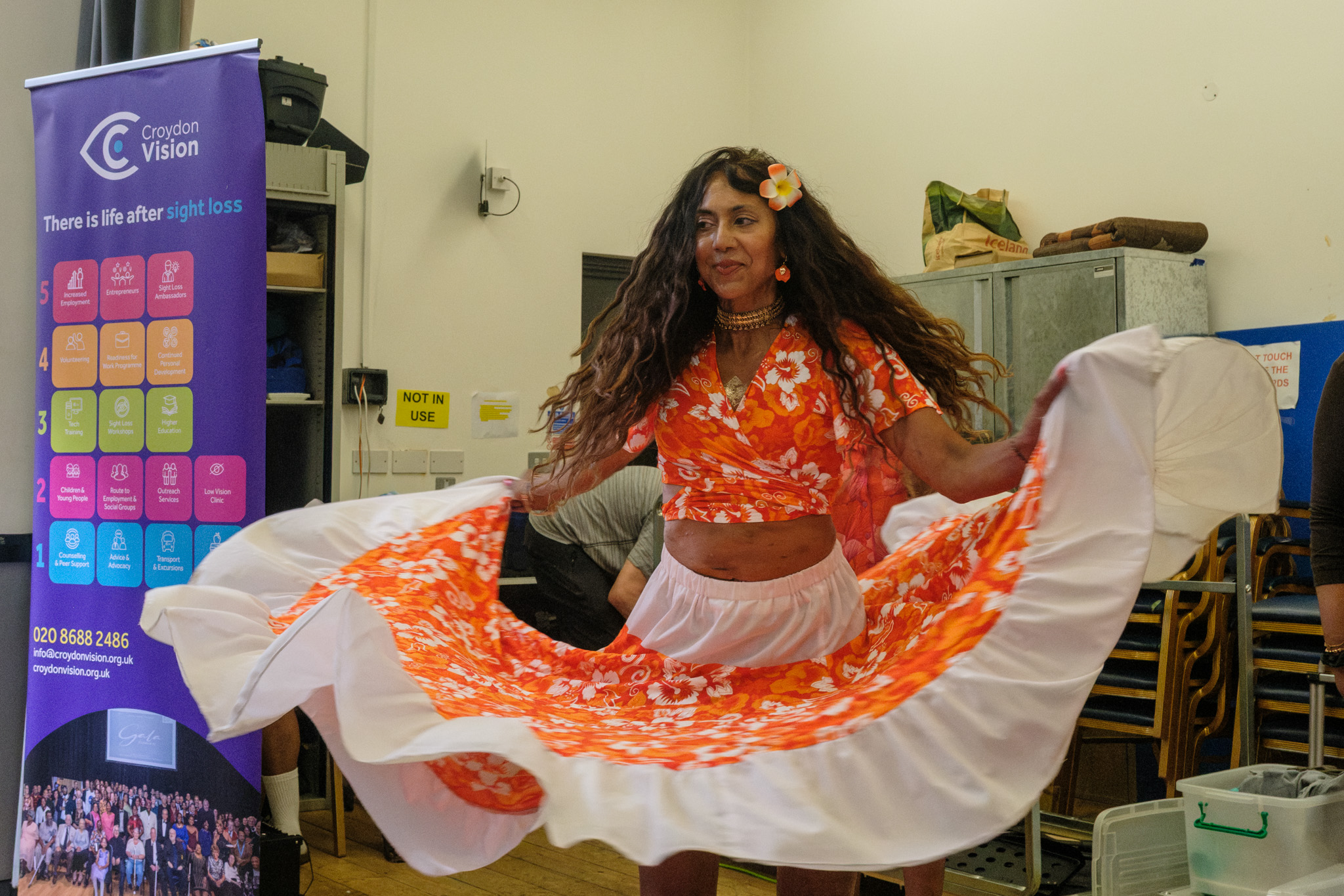 Nisha performing Mauritian Sega dance in a flowing orange-and-white costume beside a Croydon Vision banner.