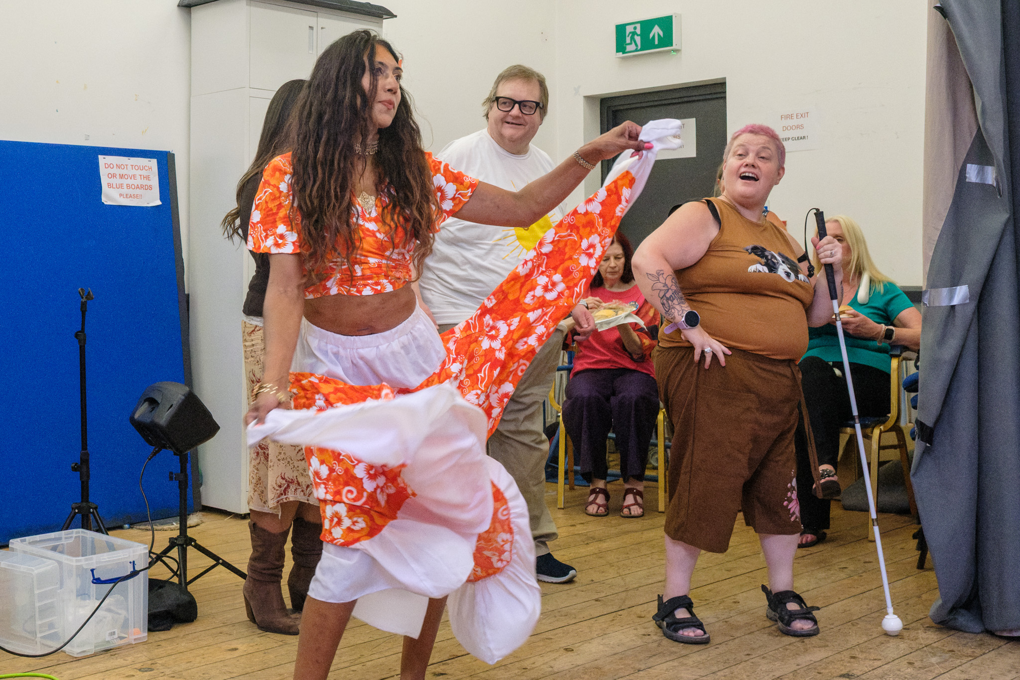 Nisha dancing with a smiling guest holding a white cane as other guests watch.